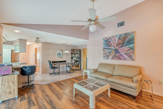 living room featuring ceiling fan, light hardwood / wood-style floors, a textured ceiling, and vaulted ceiling