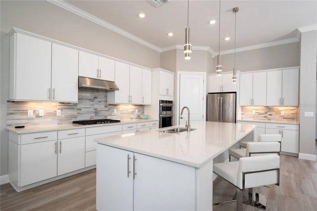 kitchen with white cabinets, appliances with stainless steel finishes, and an island with sink