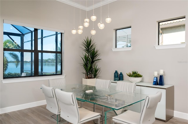 dining area with light hardwood / wood-style floors, ornamental molding, a wealth of natural light, and a chandelier