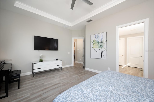 bedroom with a tray ceiling, light hardwood / wood-style flooring, ceiling fan, and ornamental molding