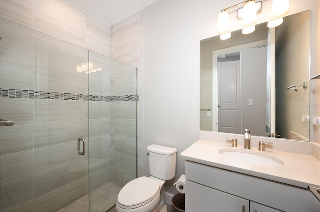 bathroom featuring a shower with door, vanity, and toilet