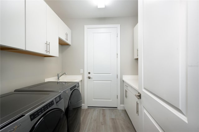 laundry room featuring washer and dryer, cabinets, light wood-type flooring, and sink