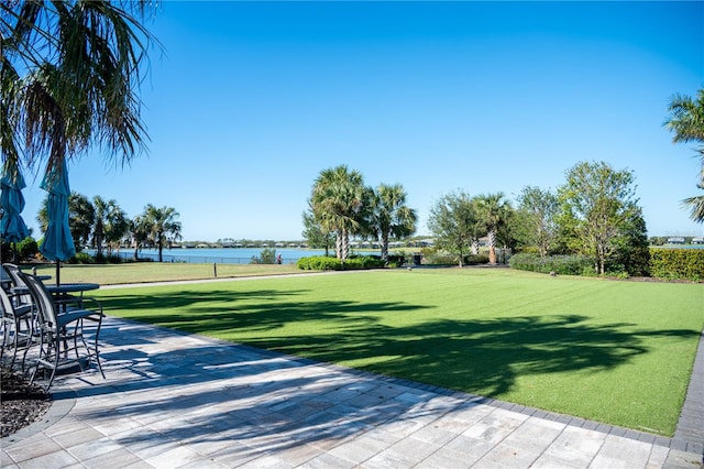 view of home's community featuring a water view, a patio area, and a lawn