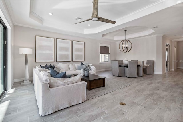 living room with ceiling fan with notable chandelier, a tray ceiling, and ornamental molding