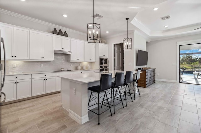 kitchen featuring white cabinetry, an island with sink, and decorative light fixtures