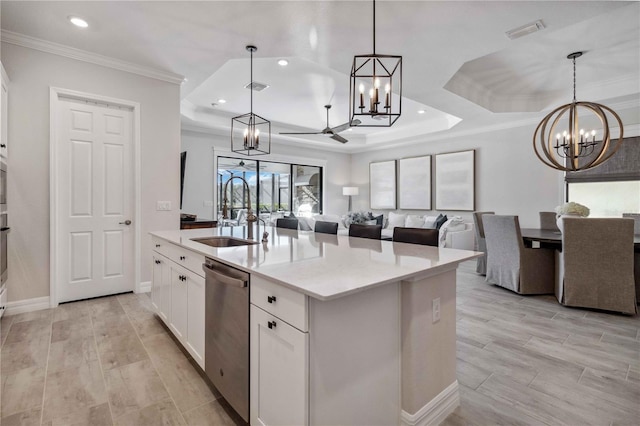 kitchen with stainless steel dishwasher, a kitchen island with sink, sink, white cabinetry, and hanging light fixtures