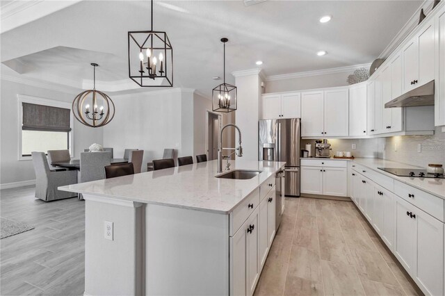 kitchen featuring sink, white cabinetry, hanging light fixtures, and an island with sink