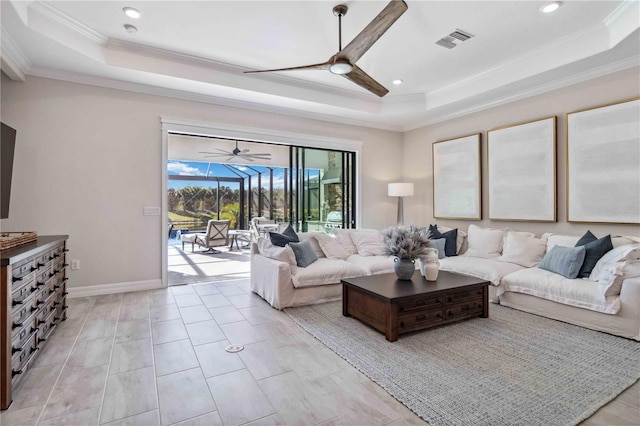 living room featuring a tray ceiling, ceiling fan, and ornamental molding