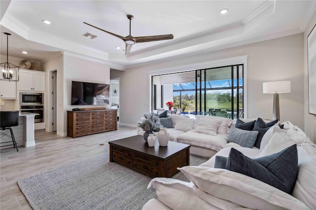 living room featuring a raised ceiling, ceiling fan, and crown molding