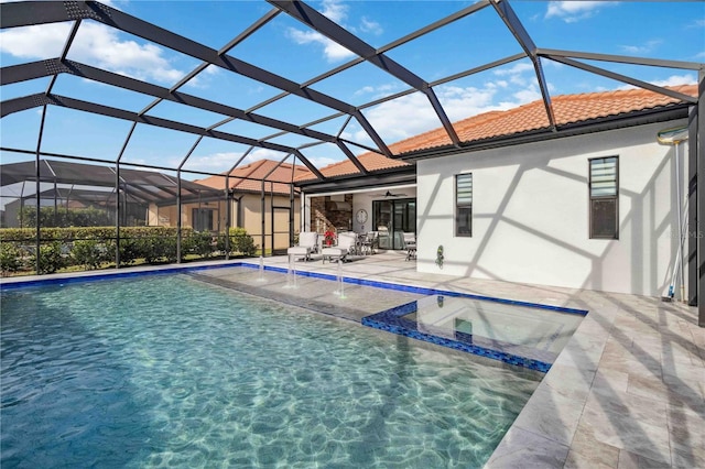 view of swimming pool with pool water feature, ceiling fan, a patio area, and a lanai