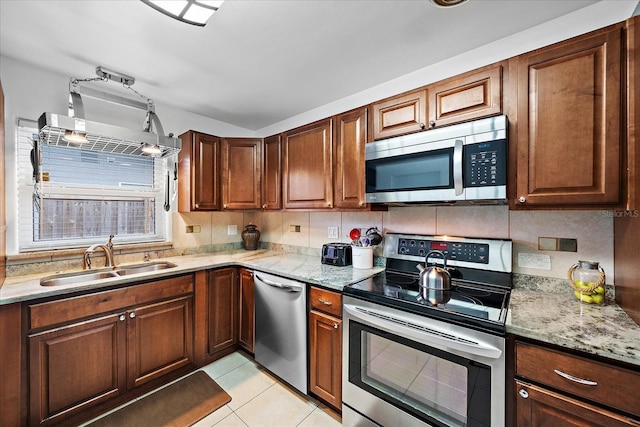 kitchen with light stone countertops, sink, stainless steel appliances, decorative backsplash, and light tile patterned flooring