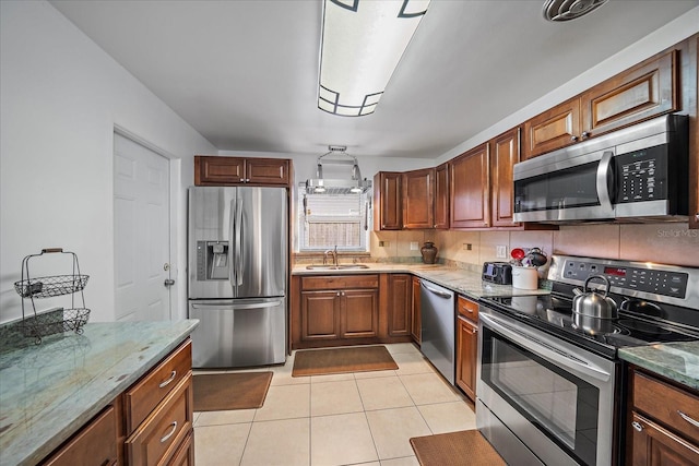 kitchen with light tile patterned floors, light stone countertops, sink, and appliances with stainless steel finishes