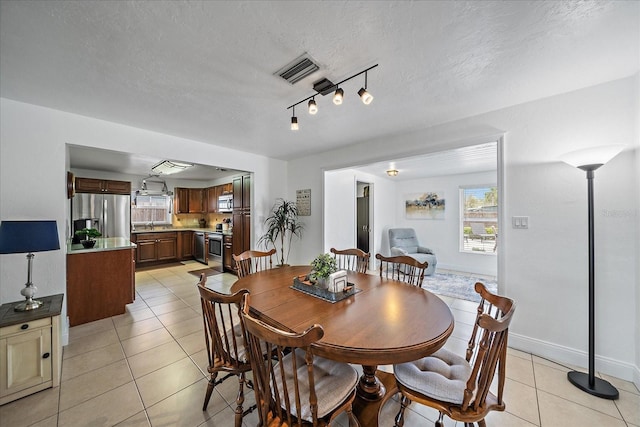 dining space with light tile patterned floors, a textured ceiling, and rail lighting