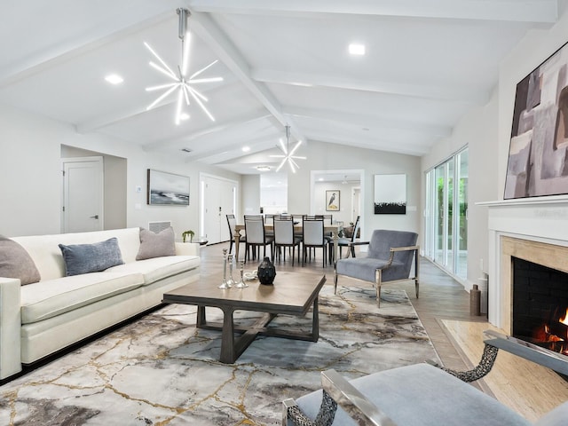 living room with a fireplace, lofted ceiling with beams, an inviting chandelier, and light hardwood / wood-style flooring