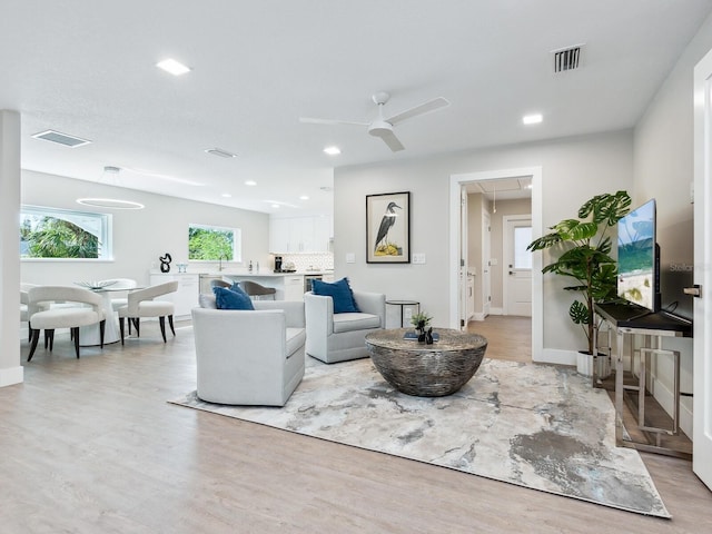 living room with light hardwood / wood-style flooring and ceiling fan