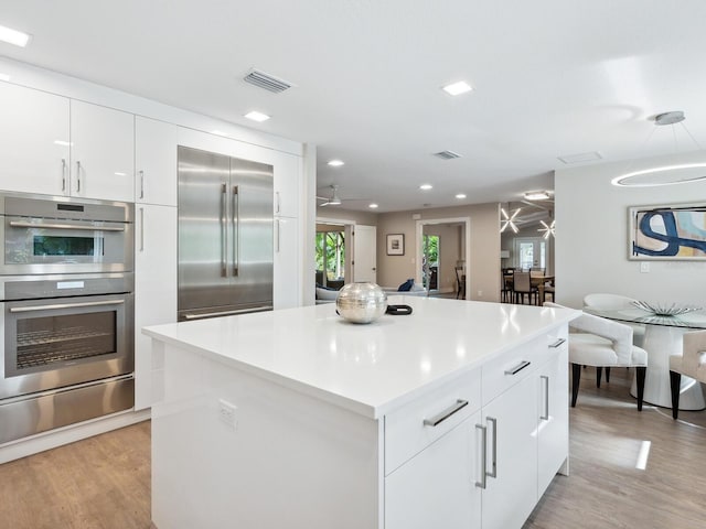 kitchen with light wood-type flooring, white cabinetry, and appliances with stainless steel finishes