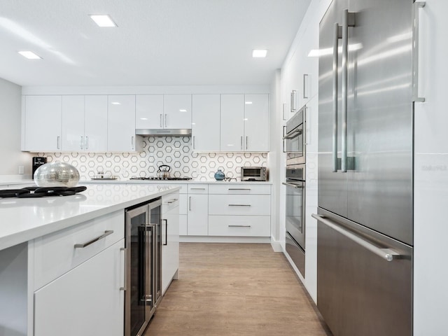 kitchen with white cabinets, wine cooler, decorative backsplash, light hardwood / wood-style floors, and stainless steel appliances