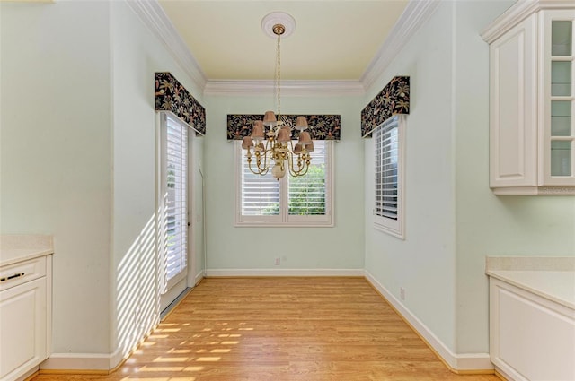 unfurnished dining area featuring light wood-type flooring, crown molding, and a chandelier