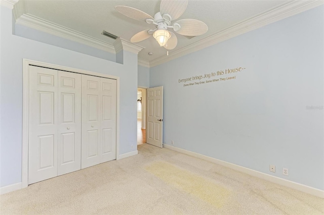 unfurnished bedroom with ceiling fan, a closet, light colored carpet, and crown molding