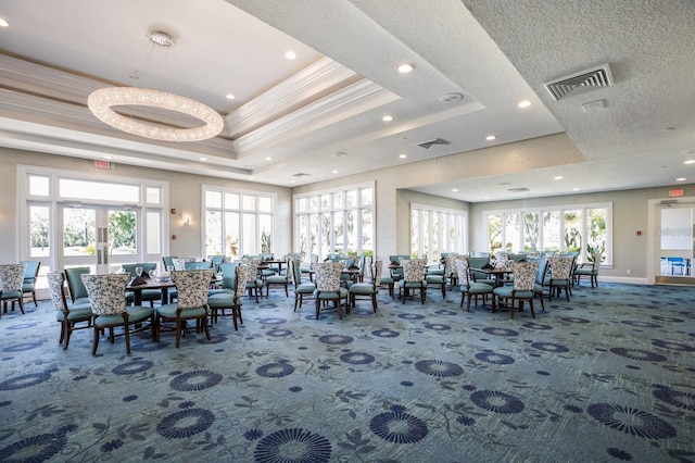 carpeted dining area with a tray ceiling, a healthy amount of sunlight, and ornamental molding