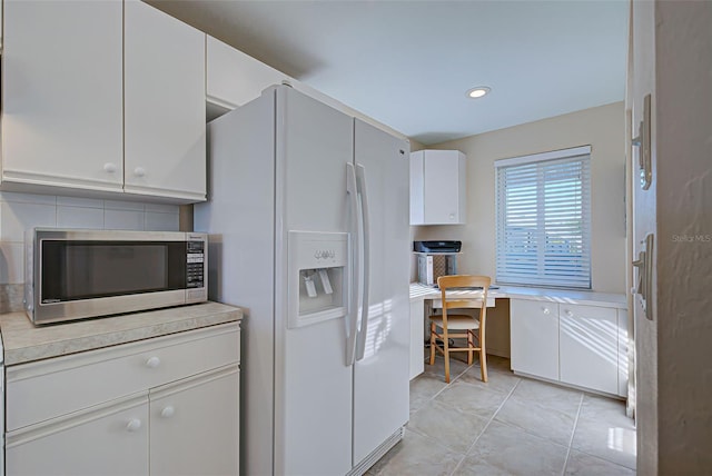 kitchen with light tile patterned floors, white cabinetry, and white fridge with ice dispenser