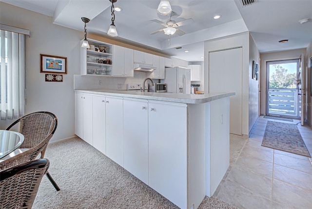 kitchen featuring white refrigerator with ice dispenser, white cabinets, sink, hanging light fixtures, and kitchen peninsula