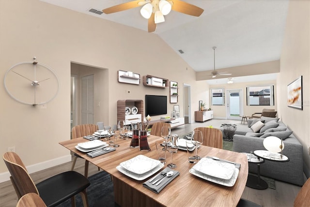 dining space featuring ceiling fan, wood-type flooring, and high vaulted ceiling