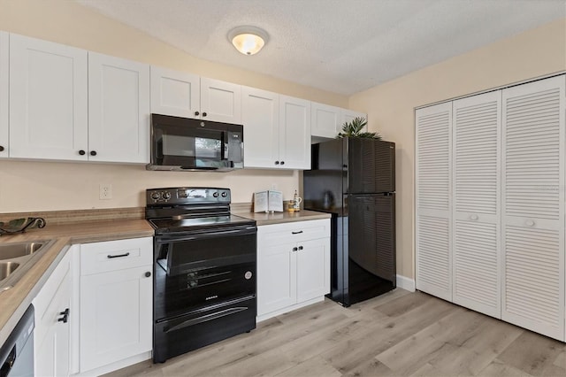 kitchen featuring wood counters, black appliances, white cabinets, light wood-type flooring, and a textured ceiling