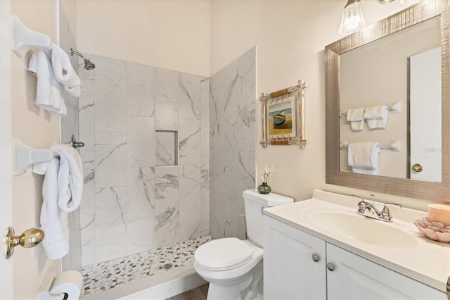 bathroom featuring tiled shower, vanity, and toilet