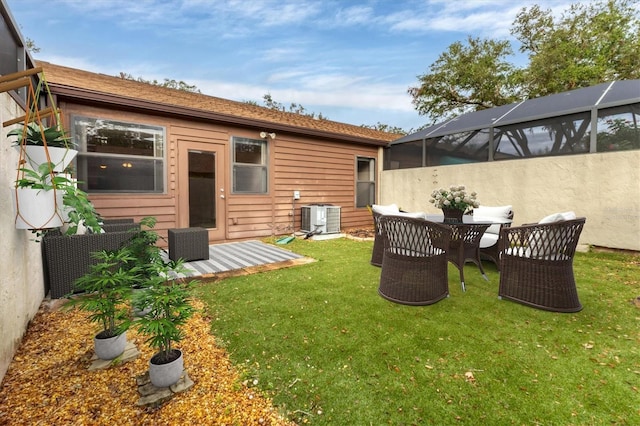 rear view of house with glass enclosure, a yard, an outdoor hangout area, and central AC unit