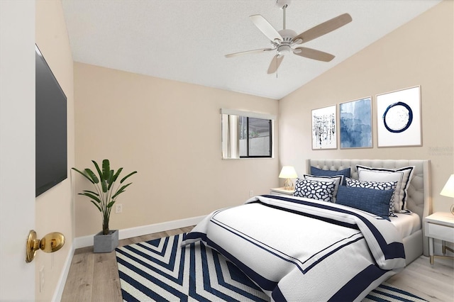 bedroom featuring ceiling fan, light hardwood / wood-style floors, and lofted ceiling