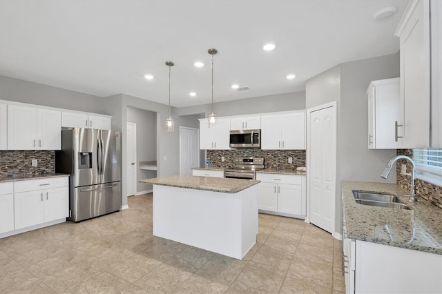 kitchen featuring hanging light fixtures, sink, appliances with stainless steel finishes, a kitchen island, and white cabinetry