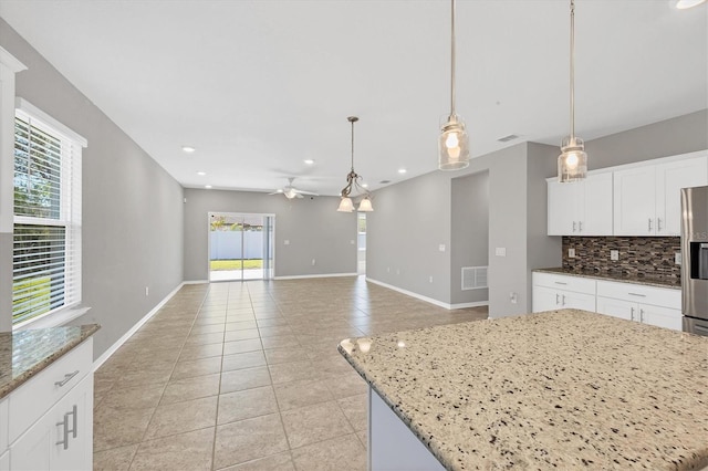 kitchen featuring white cabinetry, ceiling fan, light stone counters, pendant lighting, and a kitchen island