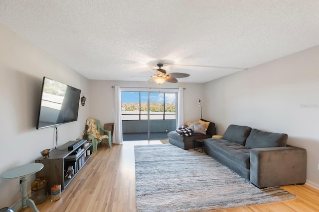 living room featuring ceiling fan, a textured ceiling, and hardwood / wood-style flooring