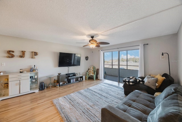 living room with a textured ceiling, light hardwood / wood-style flooring, and ceiling fan