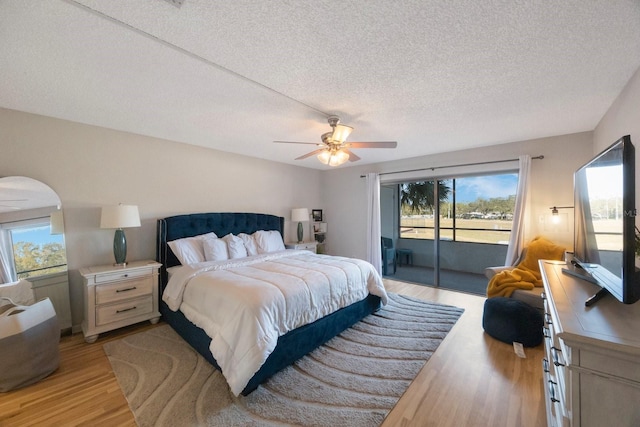 bedroom with access to exterior, ceiling fan, a textured ceiling, and light wood-type flooring