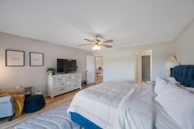 bedroom with a textured ceiling, light wood-type flooring, and ceiling fan