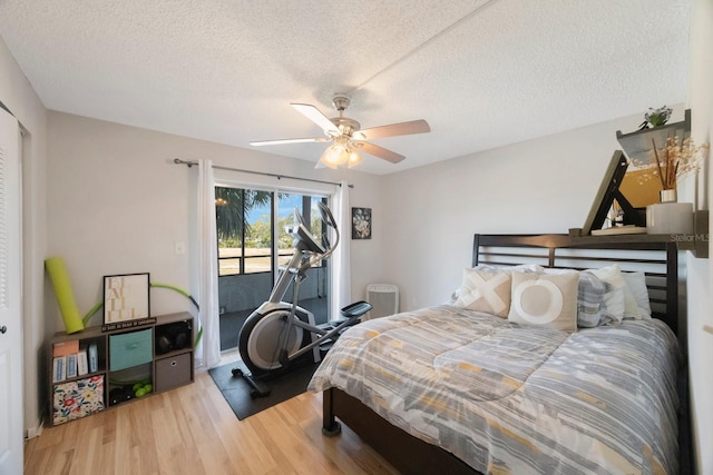 bedroom featuring access to outside, ceiling fan, hardwood / wood-style floors, and a textured ceiling