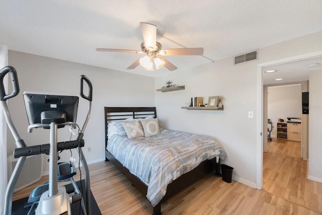 bedroom with a textured ceiling, light wood-type flooring, and ceiling fan