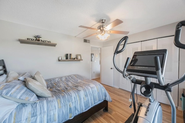 bedroom with ceiling fan, a closet, wood-type flooring, and a textured ceiling