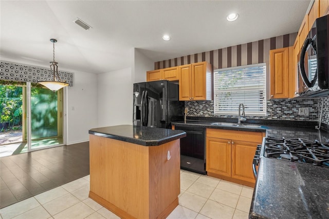 kitchen with sink, hanging light fixtures, backsplash, a kitchen island, and black appliances