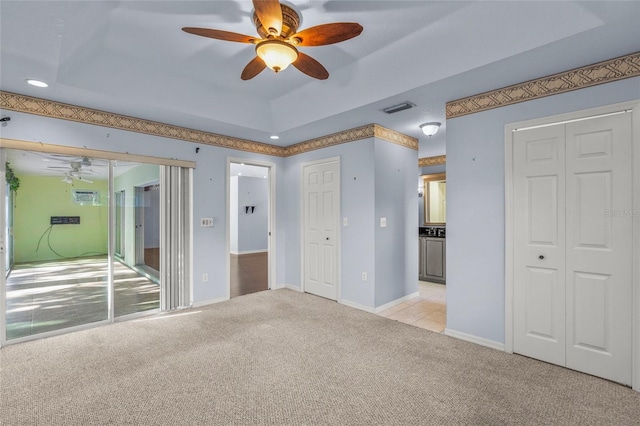 interior space featuring a tray ceiling, ceiling fan, and light colored carpet