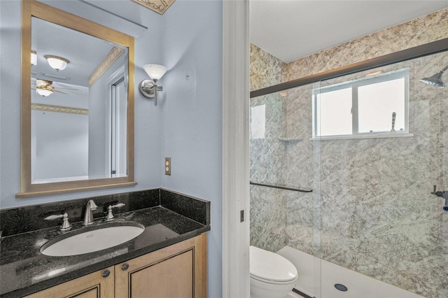 bathroom with ceiling fan, a shower with door, vanity, and toilet