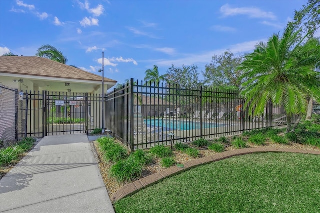 view of gate featuring a lawn and a community pool