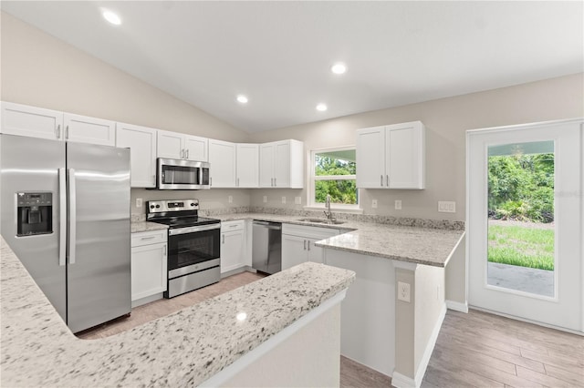 kitchen featuring a healthy amount of sunlight, white cabinets, stainless steel appliances, and lofted ceiling