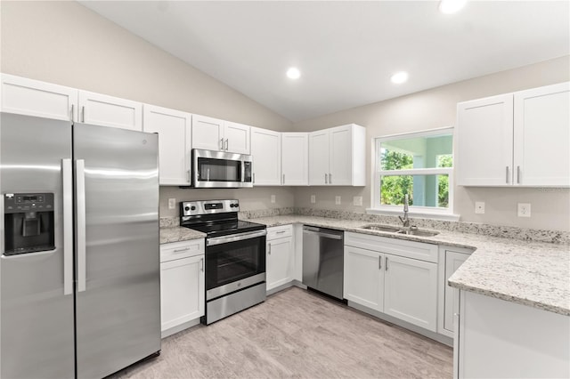 kitchen featuring sink, white cabinetry, stainless steel appliances, and vaulted ceiling