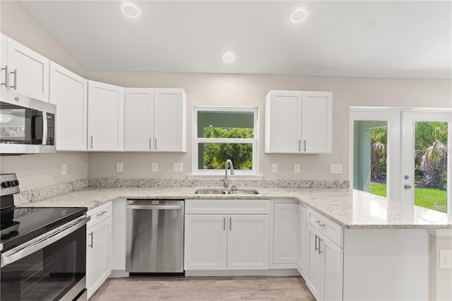 kitchen with a wealth of natural light, white cabinetry, sink, and appliances with stainless steel finishes