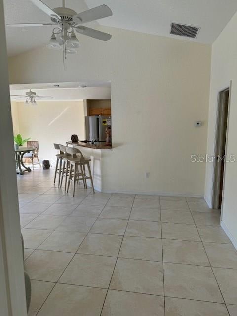 interior space featuring ceiling fan, light tile patterned floors, and vaulted ceiling