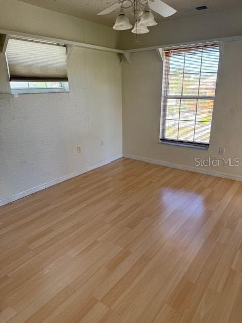 empty room with ceiling fan and light hardwood / wood-style flooring