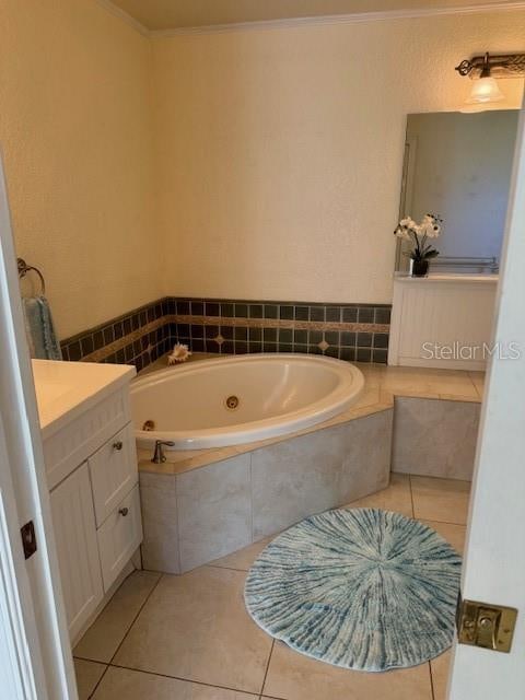 bathroom with tile patterned floors, vanity, a relaxing tiled tub, and ornamental molding